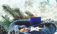 A blue scarf wrapped around a blue candle with other holiday decor.