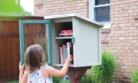 A little girl looks at the books in a Little Free Library.