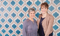 The two women behind Gypsy Mint Stencil Co. pose in front of some stencil work.