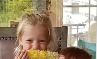 Summer Smiles & Sweet Corn Two children smile while eating sweet corn in this Lens on St. Croix Valley winning photograph.