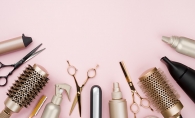 A row of various beauty products on a pink background.