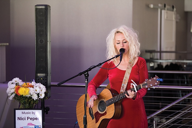 A woman plays guitar and sings at United by the Vine 2019.