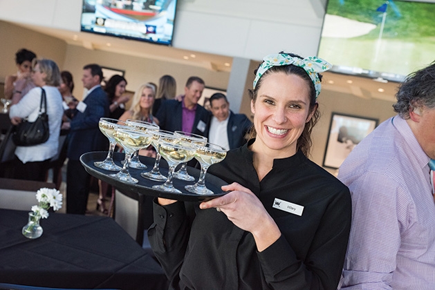A waitress smiles while serving drinks at United by the Vine 2019.