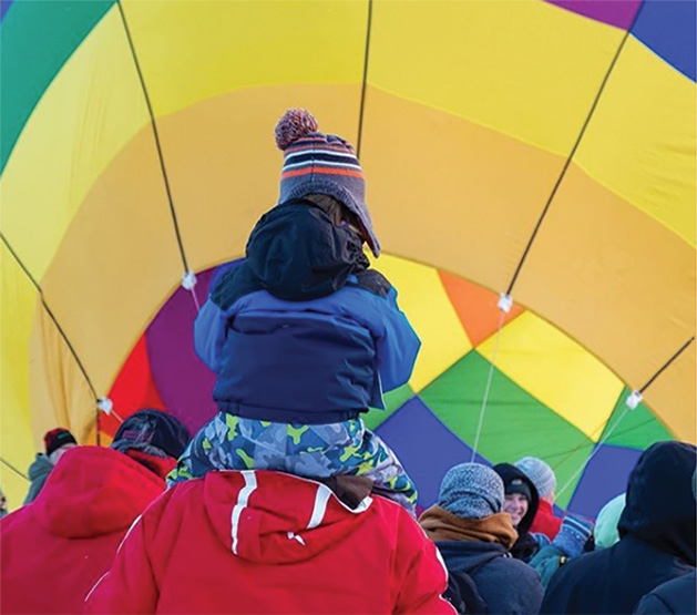 A child on an adult's shoulders watched balloons at the Hudson Hot Air Affair 2020.