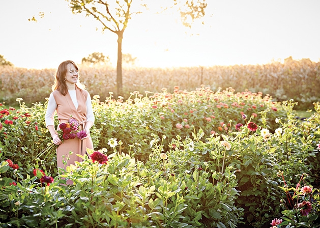 Ashley Fox Designs Floral designer Ashley Fox stands in a field of flowers.