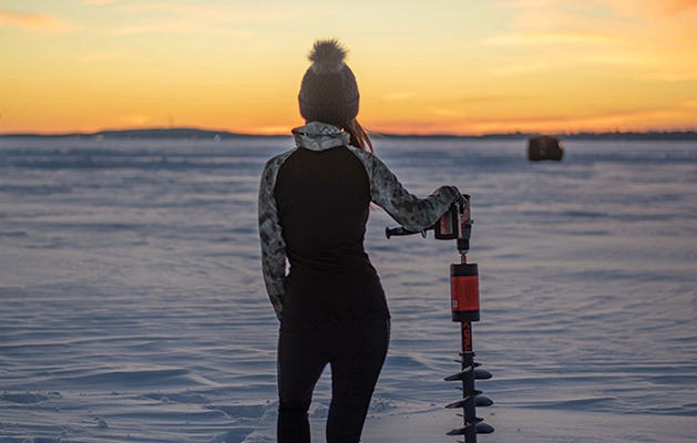 Standing with an ice auger on frozen lake