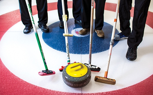 St. Croix Curling Center Curlers at the St. Croix Curling Center hold their brushes near a stone.