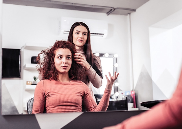 A woman talks to her hairstylist while getting a haircut.