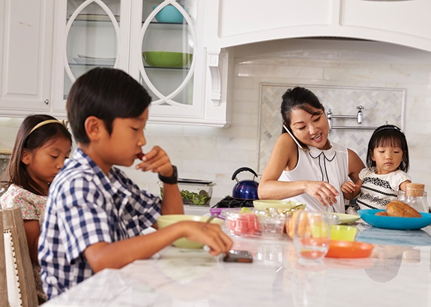 A mother talks on the phone while feeding her three children