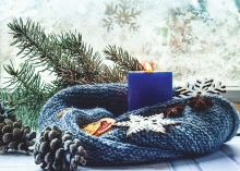 A blue scarf wrapped around a blue candle with other holiday decor.