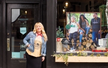 Sarah Schroeder, founder of Minnesota Made apparel company, poses outside a storefront displaying some of her products