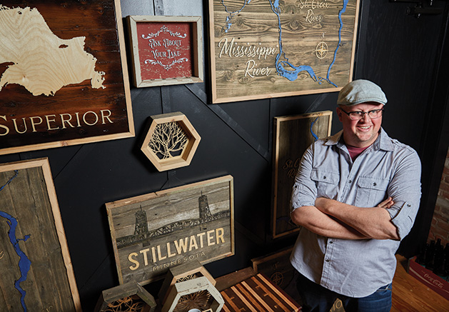 Tom Velure stands before some of his custom wood lake maps at Smith + Trade Mercantile